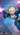 Digital illustration of a female game character in a dynamic action pose, wearing a dark teal and black outfit with a blue corset-style top, thigh-high boots, and holding two pistols. The background is a blurred futuristic cityscape with blue and purple neon lighting.